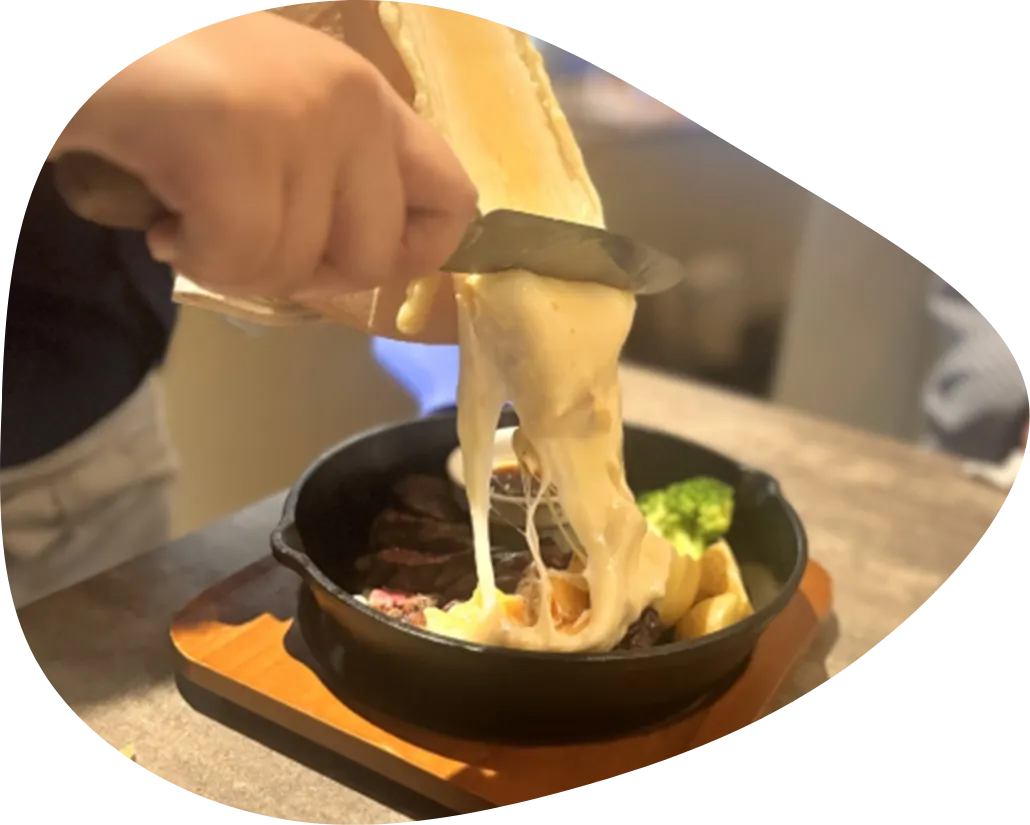 とろけるラクレットチーズを野菜にかけている写真